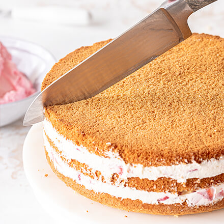 Erdbeerherz-Torte backen: den Kuchen in Form schneiden Buiskuitboden wird mit dem Messer mittig angeschnitten