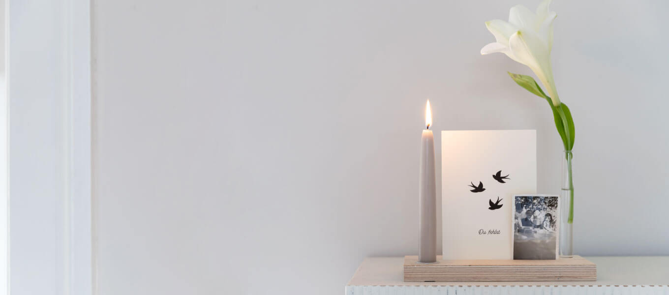 kleine Holzleiste, mit Trauerkarte, weißer Blume, einem Foto und einer Kerze