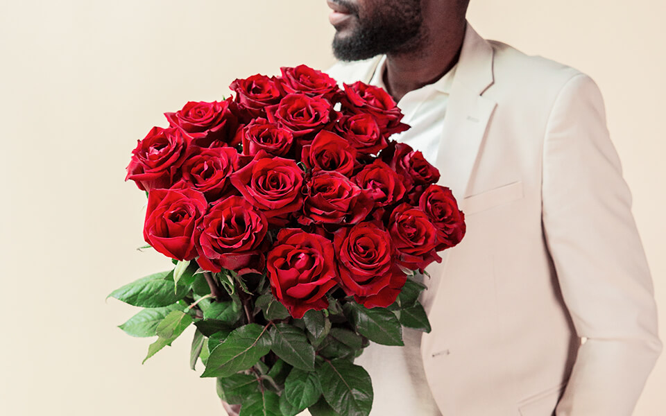 Ein Mann hält einen riesigen Strauß rote Rosen.