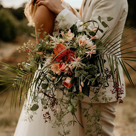 Blumendeko Hippie-Hochzeit Brautpaar mit einem Brautstrauß im Boho Stil