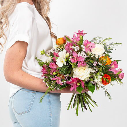 Blog Beitrag Garten im Frühling 440x440 Eine Frau hält einen weiß, pink, orangenen Blumenstrauß in der Hand.