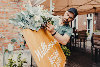 Hochzeitsfloristik Florist dekoriert Willkommenstafel mit Blumen