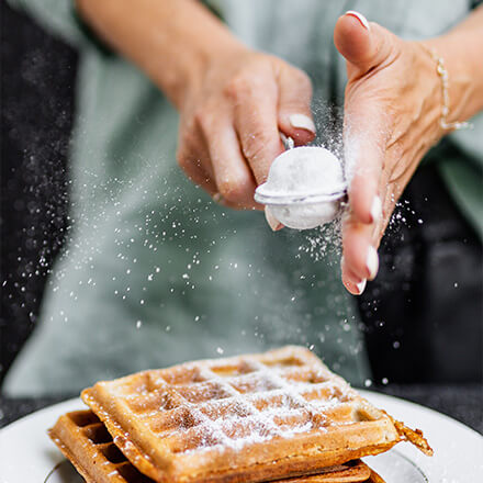 Frühstückswaffeln Person bestreut Waffel mit Puderzucker