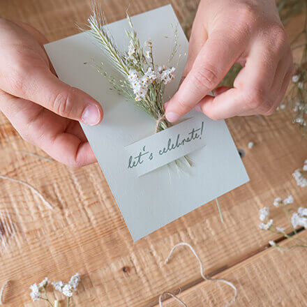 Hochzeitseinladungen mit Trockenblumen - Step 3 Ein Mini-Trockenblumenstrauß wird durch einen Schlitz in einer Hochzeitseinladungskarte gesteckt