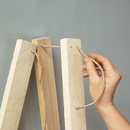 Blog Beitrag Alternativ Weihnachtsbaum Step3 Eine Holzkordel wird durch die Löcher in den Brettern gezogen.