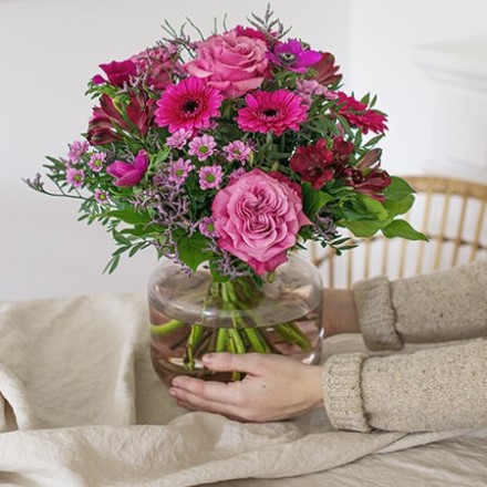 1. Schaffe Dir eine angenehme Atmosphäre. pinker Blumenstrauß wird in einer Vase auf den Tisch gestellt