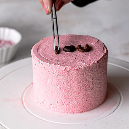 Valentinstag-Torte: Schokobuchstaben auf das Törtchen setzen Torte wird mit Schokobuchstaben dekoriert