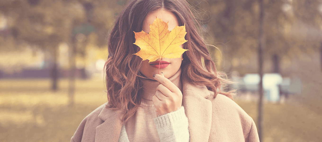 Blog Header Herbst 1360x600px Herbstbild. Eine Frau hält ein Herbstblatt nach oben