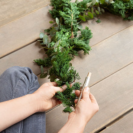 Blog Beitrag Alternativ Weihnachtsbaum Step5 Es wird eine Girlande aus Tanne und Eukalyptus gebunden.