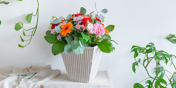 Upcycling-Idee einer Flower-Bag zu einer Vase mit Bambusstäben, die senkrecht an der Flower-Bag angebracht worden sind und danach farblich mit Kreidefarbe in Taupe gestaltet wurde.