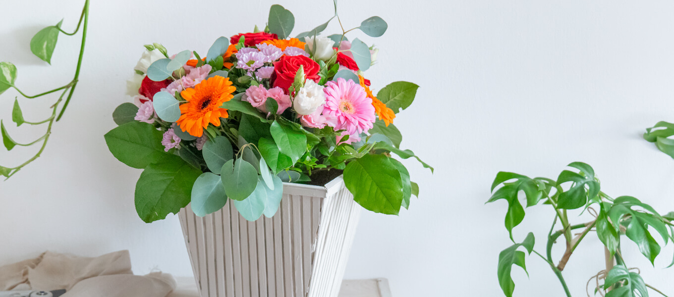 Flower-Bag-Upcycling zur Vase Upcycling-Idee einer Flower-Bag zu einer Vase mit Bambusstäben, die senkrecht an der Flower-Bag angebracht worden sind und danach farblich mit Kreidefarbe in Taupe gestaltet wurde.
