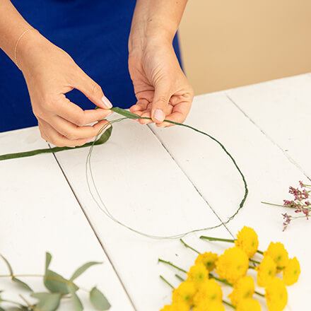 DIY: Haarkranz selbst basteln - Step 2: Grundgerüst mit Floristentape umwickeln Zwei Hände wickeln Floristentape um einen Kreis aus Draht.