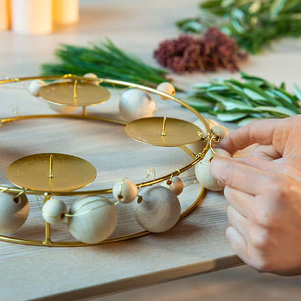 Blog Beitrag Adventskranz Step3 Nun wird das Band mit den kleinen Holzkugeln ebenfalls um den Advenstskranz gewickelt.