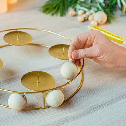 Blog Beitrag Adventskranz Step2 Das Band mit den großen Holzkugeln wird nun an ein Adventskranz festgemacht.