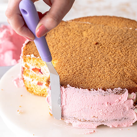 Erdbeerherz-Torte backen: Frosting Torte wird an der Kante des Kuchens mit Frosting eingestrichen