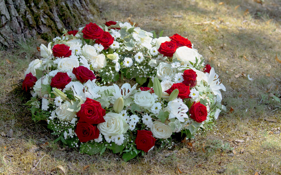 Trauergesteck in weiß-rot mit roten Rosen und weißen Lilien.