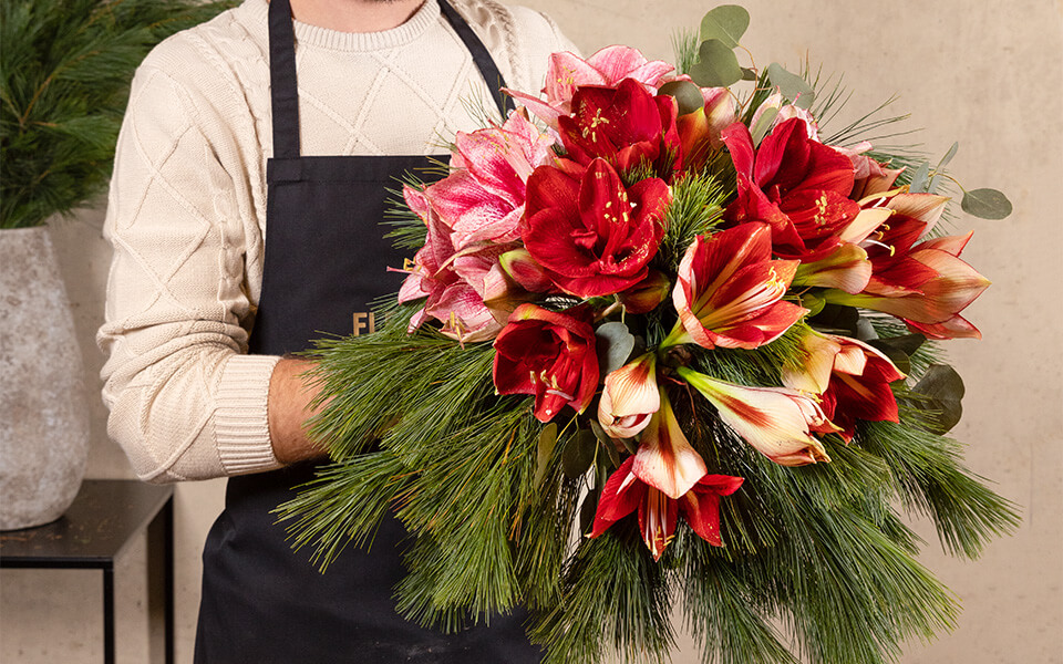 Ein Florist hält einen Amaryllisstrauß in der Hand