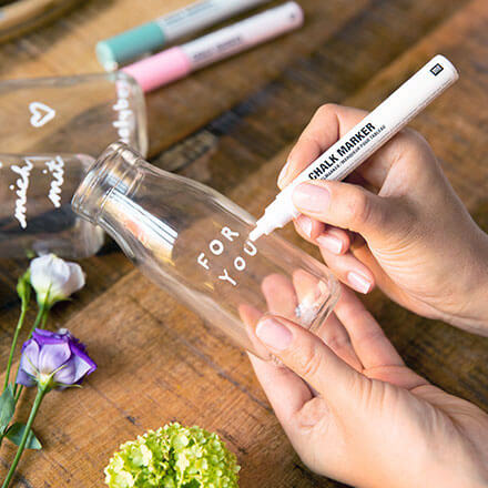 Blumen-Überraschung mit liebevoller Botschaft: Step 1: Botschaft auf das Glas schreiben Mit Hilfe von zwei Händen und Kreidefarbe wird der Schriftzug "FOR YOU" auf ein Einmachglas aufgebracht.
