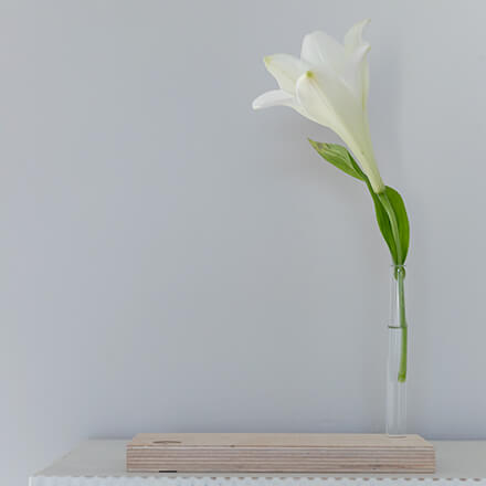 Kartenhalter aus Holz mit einem Glasröhrchen, in der eine weiße Blume steckt