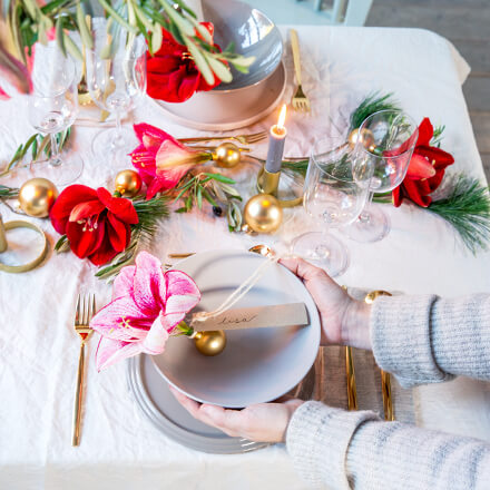 Blog Beitrag Tischdeko Weihnachten 1 Tischdekoration: Eine pinke Amaryllisblüte in eine Weihnachtskugel gesteckt und mit einem Namensschild dran.