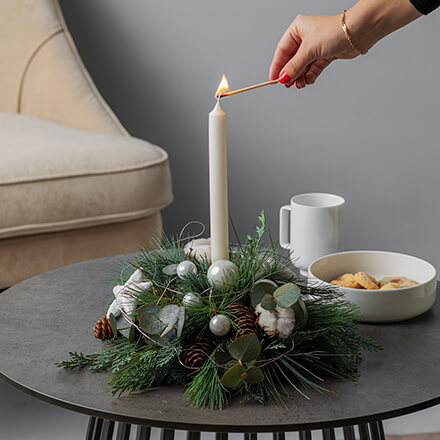 Blog Beitrag Adventskranz - kleines Adventsgesteck Kleines Adventsgesteck mit einer Kerze und klassischer Dekoration wie Tannenzweige und Kugeln.
