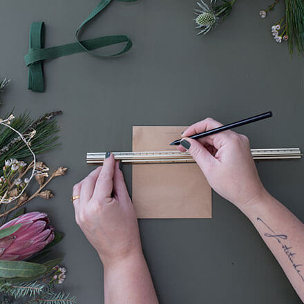 Adventskalender Step1 Blog Mithilfe eines Lineals und einem Bleistift werden zwei gleich lange Striche oberhalb der brauen Tüte und eine unterhalb des knicks gezogen.