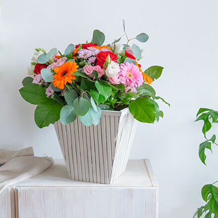 Upcycling-Idee einer Flower-Bag zu einer Vase mit Bambusstäben, die senkrecht an der Flower-Bag angebracht worden sind und danach farblich mit Kreidefarbe in Taupe gestaltet wurde.