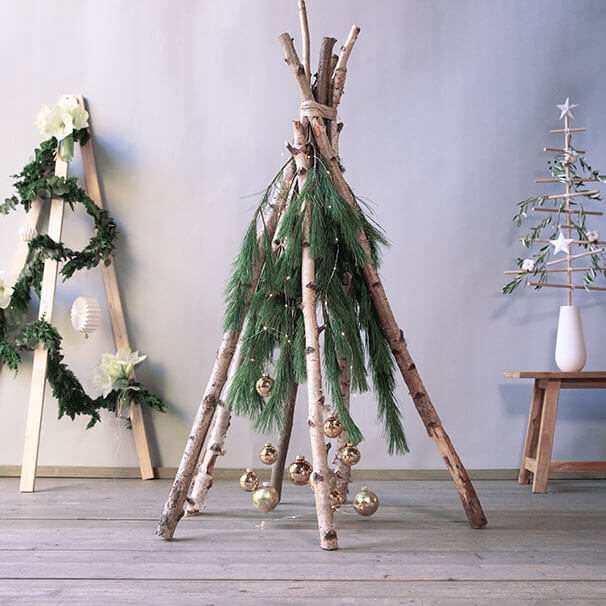 Weihnachtsbaumalternative aus Naturmaterialien wie Birkenstämme, Kiefernzweige und Amaryllis.