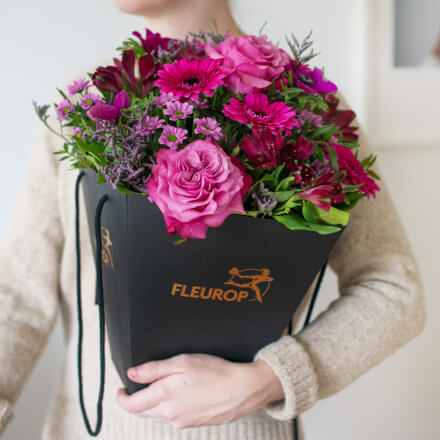 Frau hält einen pinken Valentinstagsstrauß in einer Flower-Bag im Arm